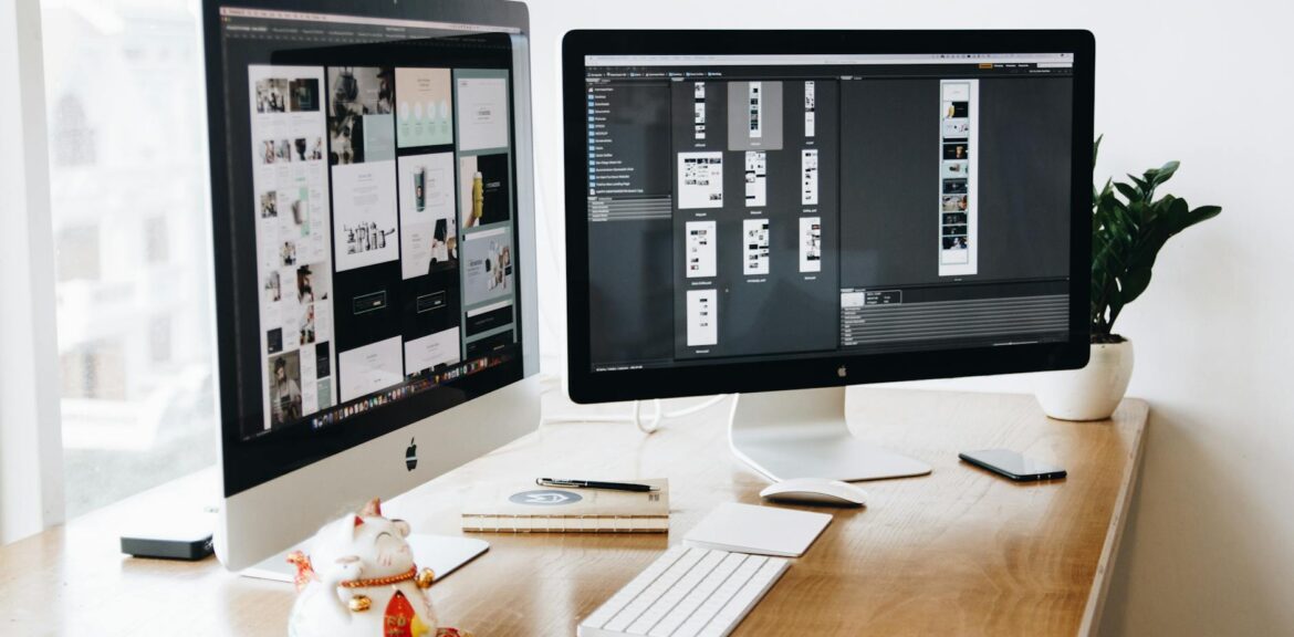 two imac s with keyboard and phones on desk